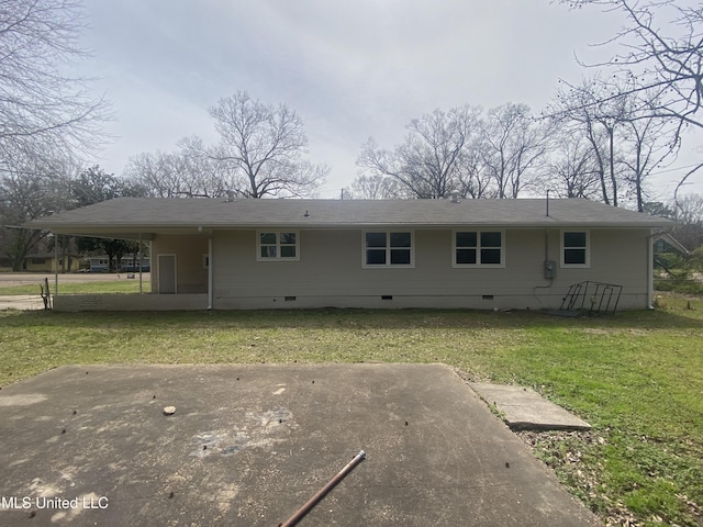 rear view of house with crawl space, an attached carport, a shingled roof, and a yard