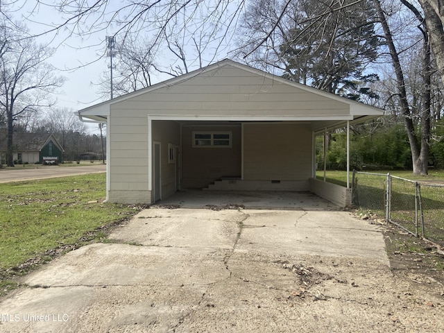 garage with a carport, concrete driveway, a gate, and fence