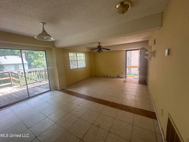 empty room featuring ceiling fan, a textured ceiling, and light tile patterned floors