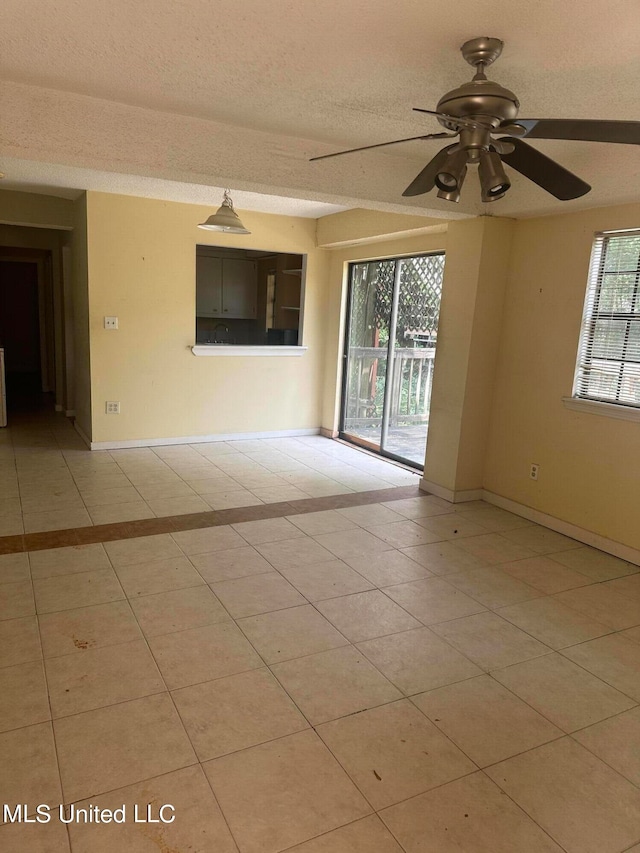 spare room with a textured ceiling, light tile patterned floors, plenty of natural light, and ceiling fan