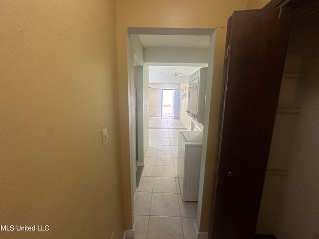 corridor with stacked washer / drying machine and light tile patterned floors