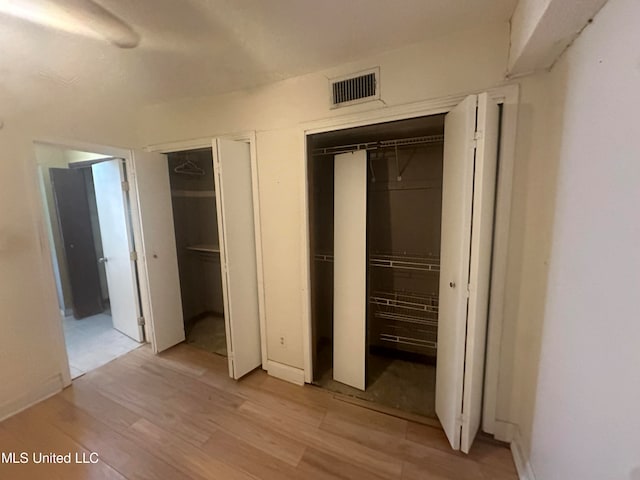 unfurnished bedroom featuring two closets and light hardwood / wood-style floors