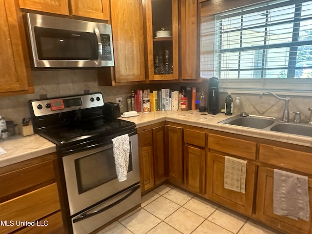 kitchen with light tile patterned flooring, stainless steel appliances, sink, and backsplash