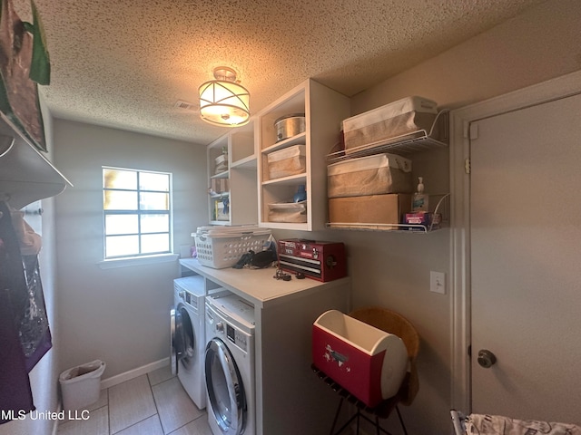 laundry area with a textured ceiling, washing machine and clothes dryer, and light tile patterned floors