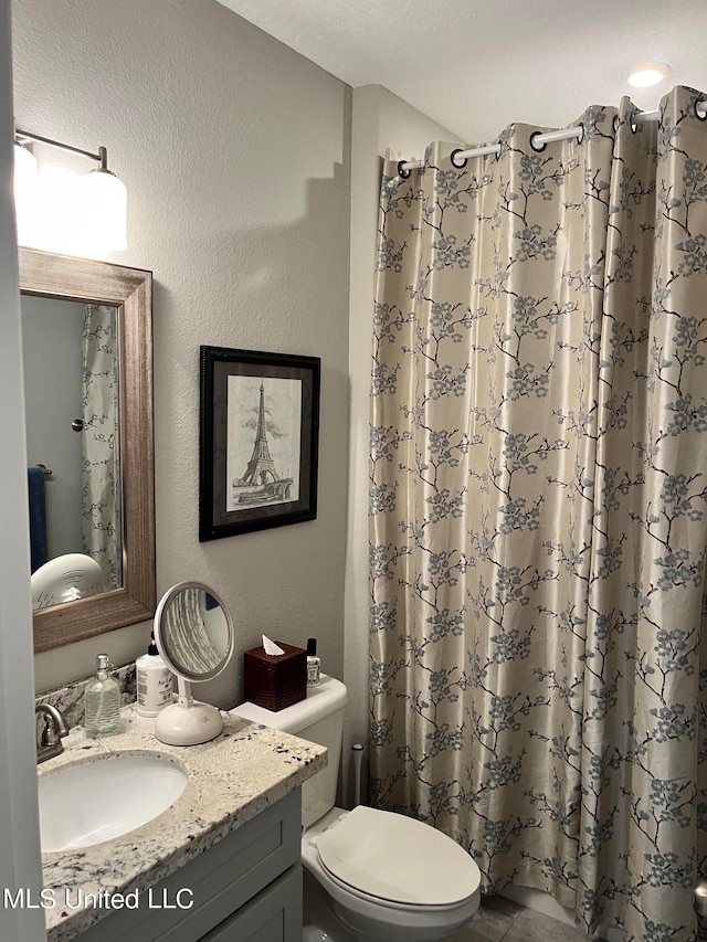 bathroom with vanity, toilet, walk in shower, and a textured ceiling