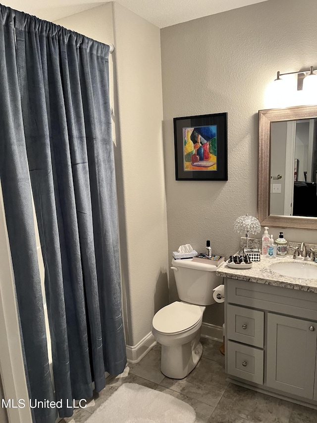 bathroom featuring toilet, vanity, and baseboards