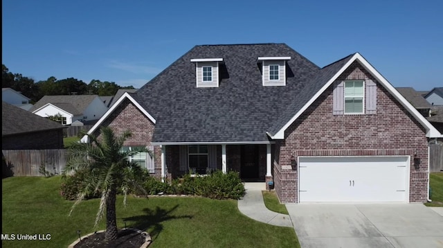view of front facade featuring brick siding, fence, a shingled roof, and a front yard