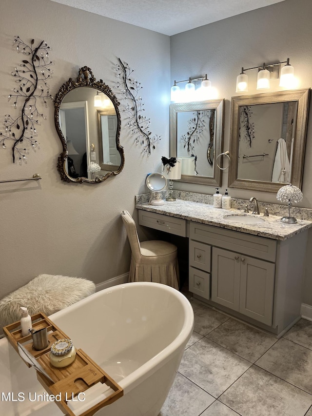 bathroom with a freestanding tub, vanity, and tile patterned flooring