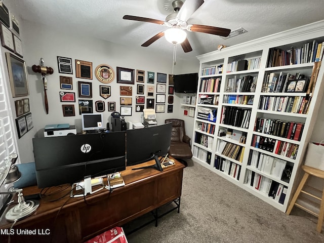 carpeted office space featuring visible vents, a ceiling fan, and a textured ceiling