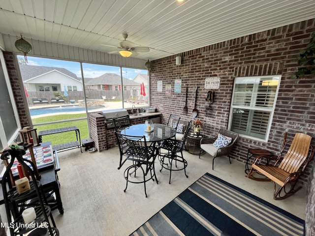 sunroom featuring a sink, a ceiling fan, and outdoor dining area