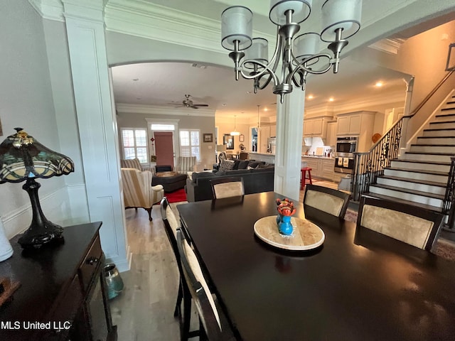 dining room featuring ornate columns, ornamental molding, wood-type flooring, and ceiling fan with notable chandelier