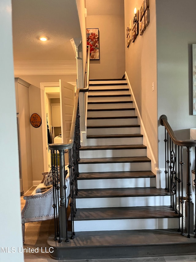 staircase with crown molding and hardwood / wood-style flooring