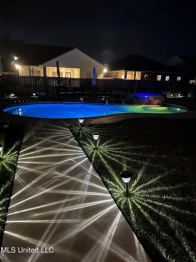 pool at night with a fenced in pool and fence