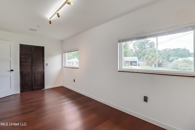 unfurnished bedroom with dark wood-type flooring and rail lighting