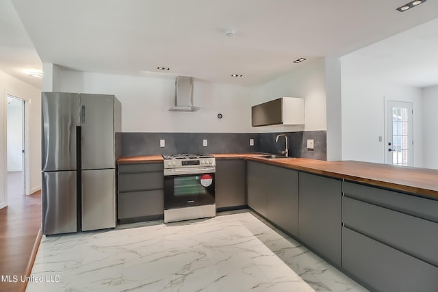 kitchen with gray cabinetry, sink, stainless steel appliances, wall chimney exhaust hood, and decorative backsplash