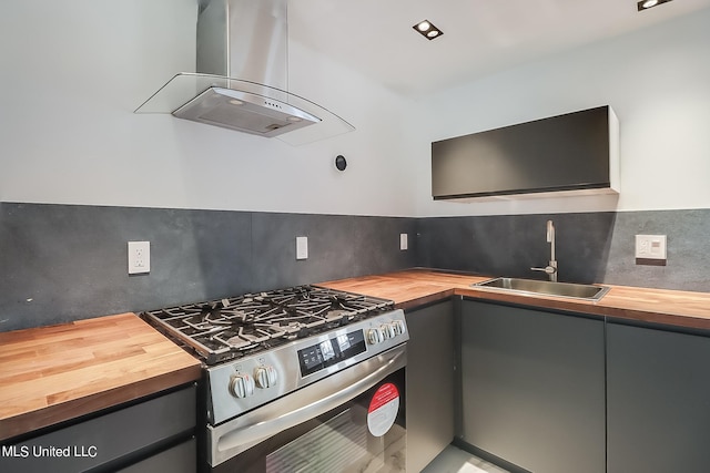 kitchen featuring sink, island range hood, backsplash, wood counters, and stainless steel stove