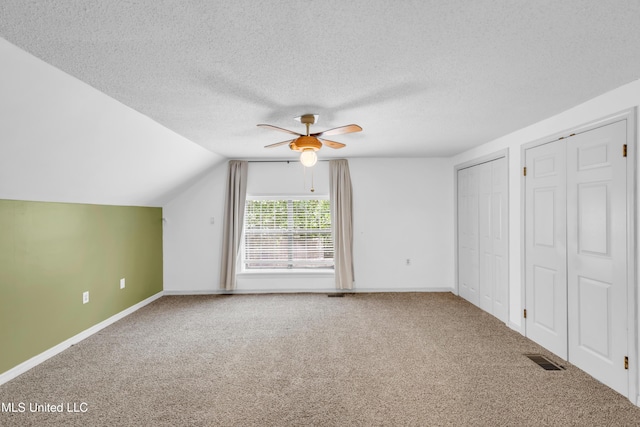 5423 Kaiki Dr, Diamondhead, MS 39525 - unfurnished bedroom with carpet, multiple closets, lofted ceiling, a textured ceiling, and a ceiling fan