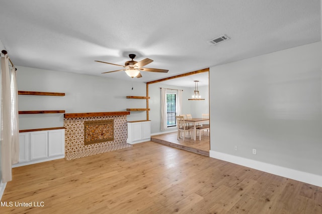 5423 Kaiki Dr, Diamondhead, MS 39525 - unfurnished living room with light wood-style floors, a ceiling fan, a chandelier, and a textured ceiling