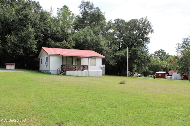 view of front of house featuring a front lawn, a storage shed, and covered porch