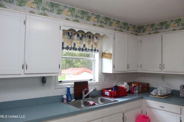 kitchen with sink, white cabinetry, and a textured ceiling