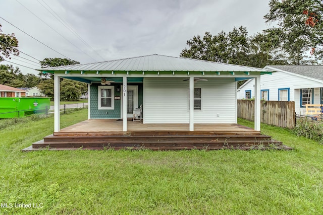 rear view of house featuring ceiling fan and a yard