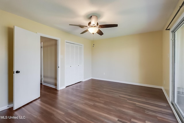 unfurnished bedroom with dark wood-style floors, a closet, baseboards, and a ceiling fan
