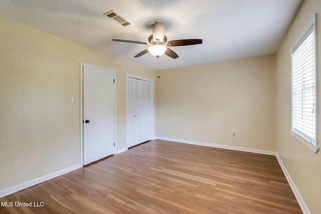 unfurnished bedroom with light wood-style flooring, baseboards, visible vents, and a textured ceiling