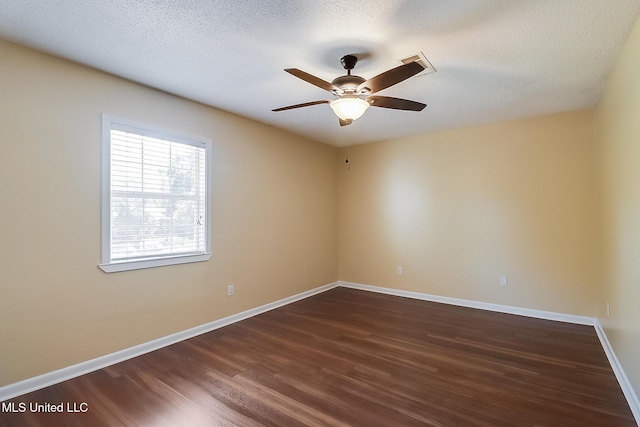spare room featuring dark wood-style floors, visible vents, baseboards, ceiling fan, and a textured ceiling