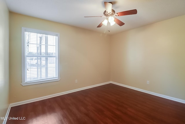 empty room featuring dark wood-type flooring, a ceiling fan, and baseboards