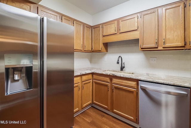 kitchen with decorative backsplash, wood finished floors, appliances with stainless steel finishes, and a sink