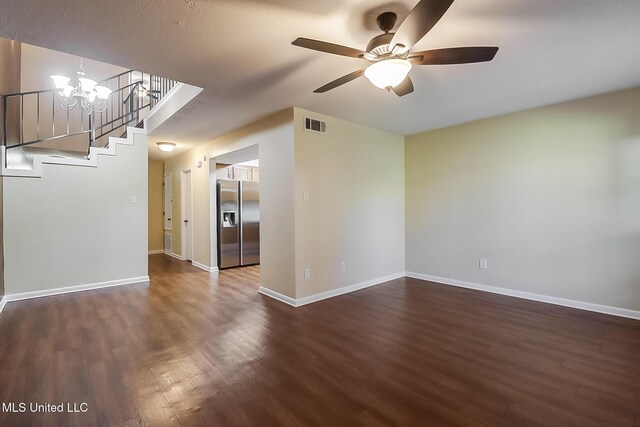spare room featuring ceiling fan with notable chandelier, baseboards, visible vents, and dark wood-style flooring