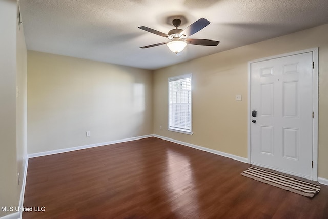 foyer with ceiling fan, a textured ceiling, dark wood-type flooring, and baseboards