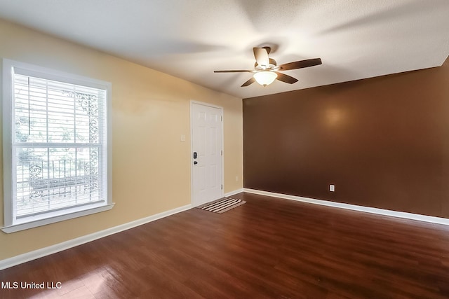 spare room with dark wood-type flooring, baseboards, and ceiling fan