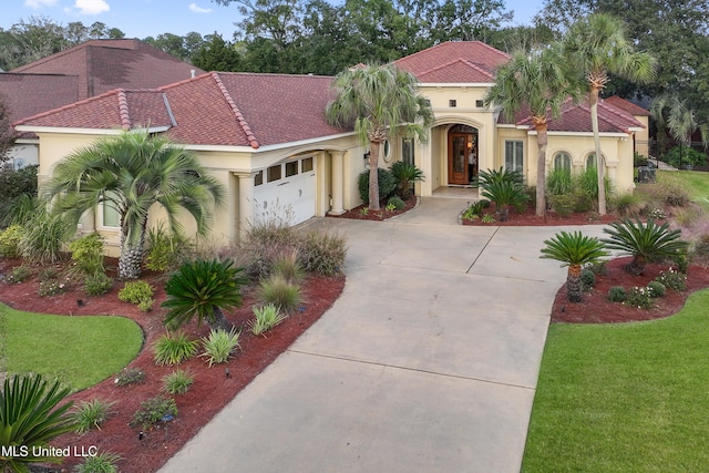 mediterranean / spanish-style house featuring a garage and a front lawn