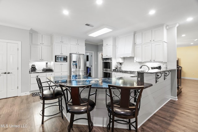 4424 Rebekah Dr, Olive Branch, MS 38654 - kitchen with stainless steel appliances, premium range hood, a breakfast bar area, tasteful backsplash, and recessed lighting