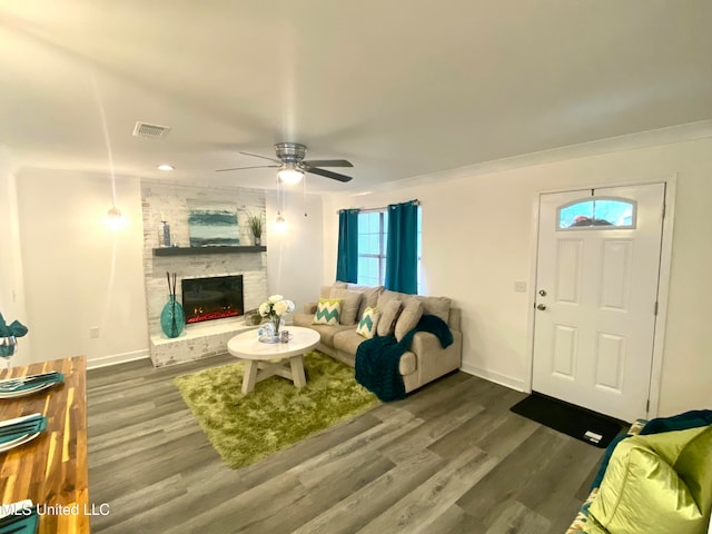 living room featuring a fireplace, crown molding, ceiling fan, and dark wood-type flooring