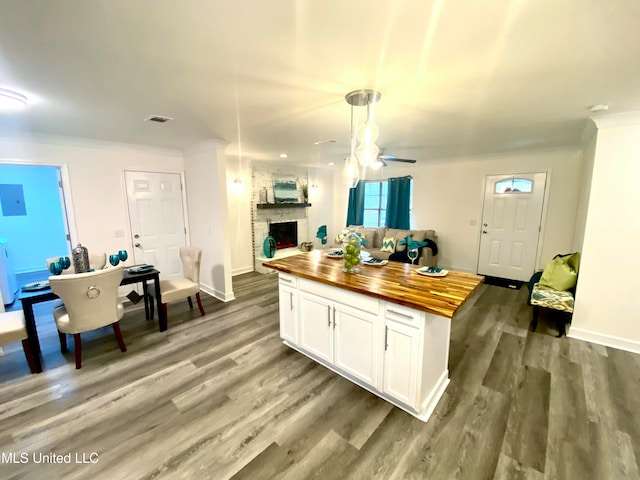 kitchen with wooden counters, a brick fireplace, white cabinetry, and hardwood / wood-style floors