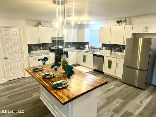 kitchen featuring white cabinetry, stainless steel appliances, decorative light fixtures, and wood counters