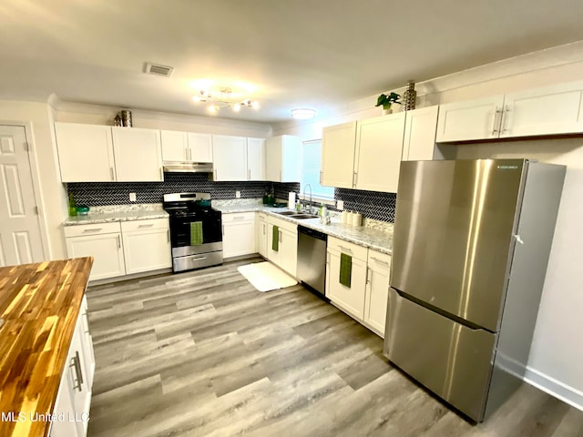 kitchen with decorative backsplash, appliances with stainless steel finishes, sink, light hardwood / wood-style flooring, and white cabinetry