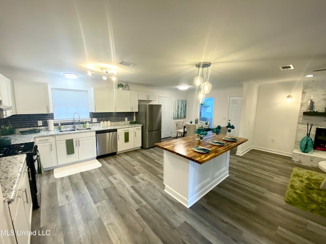 kitchen featuring stainless steel appliances, white cabinetry, and butcher block counters