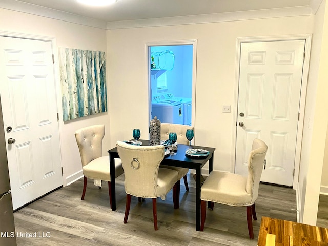 dining space with washer and dryer, wood-type flooring, and ornamental molding