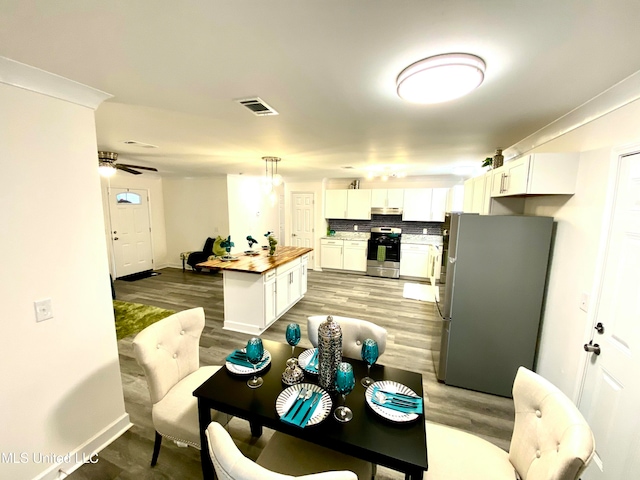 kitchen featuring butcher block counters, white cabinetry, stainless steel appliances, decorative light fixtures, and a kitchen island