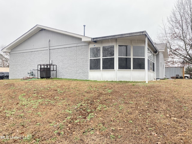 view of home's exterior with a sunroom and a lawn