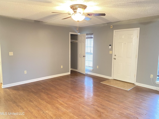 empty room with wood-type flooring, ceiling fan, and a textured ceiling