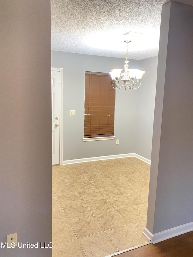 spare room with a chandelier and a textured ceiling