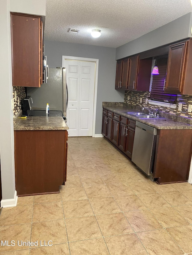 kitchen featuring sink, light tile patterned floors, dishwasher, a textured ceiling, and decorative backsplash