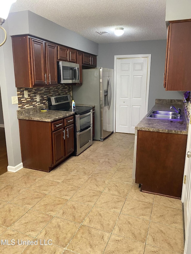 kitchen featuring sink, backsplash, a textured ceiling, and appliances with stainless steel finishes