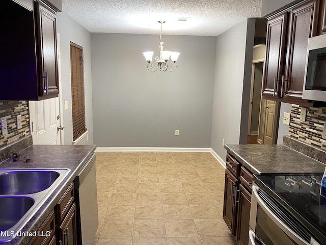 kitchen featuring appliances with stainless steel finishes, pendant lighting, an inviting chandelier, sink, and a textured ceiling