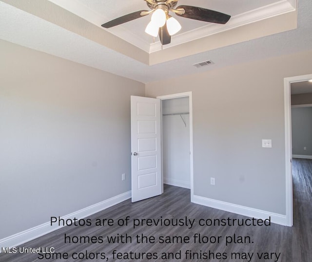 unfurnished bedroom featuring a raised ceiling, dark hardwood / wood-style floors, a closet, and ceiling fan