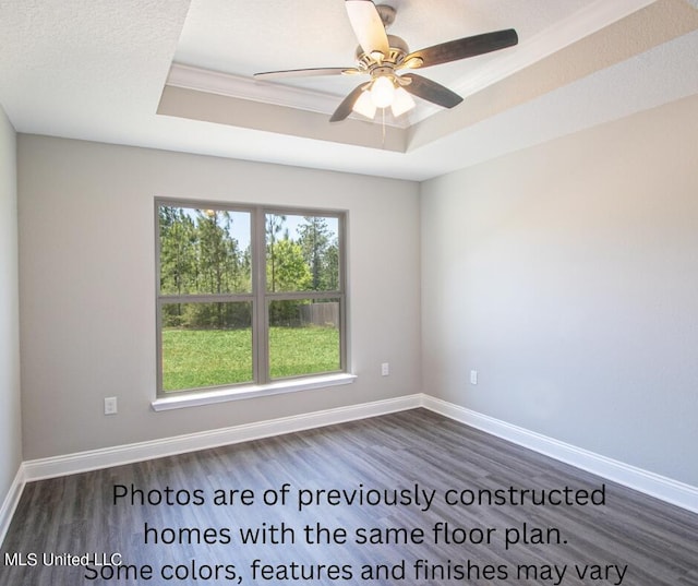 unfurnished room featuring ornamental molding, dark wood-type flooring, ceiling fan, and a raised ceiling